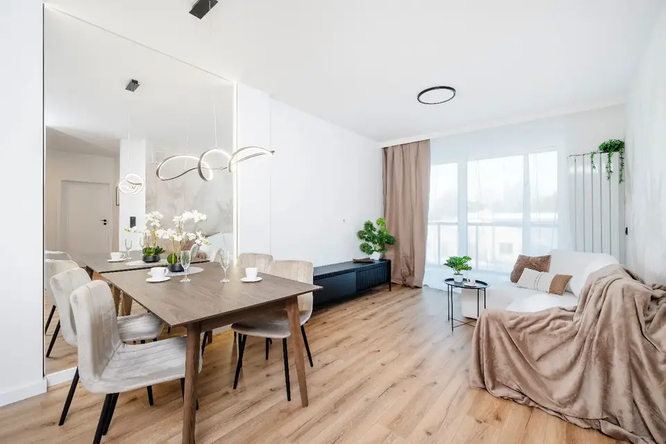 Otwarty salon z jadalnią, okrągłym stołem i balkonowym oknem