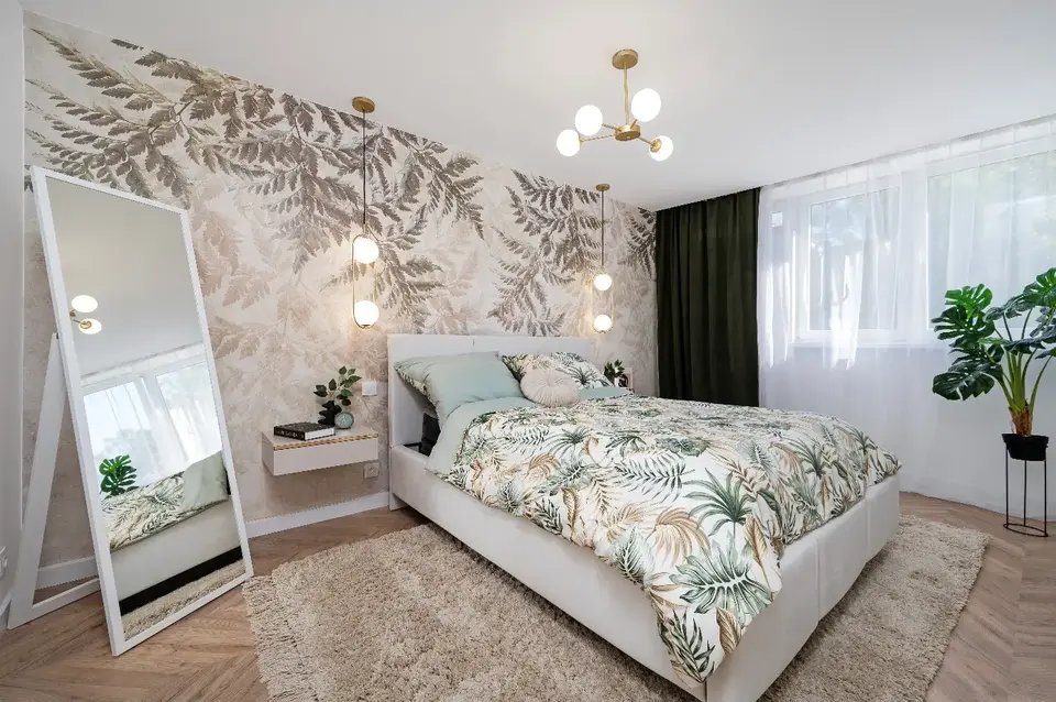 Sypialnia z botaniczną tapetą, jasną szafą i dużym lustrem